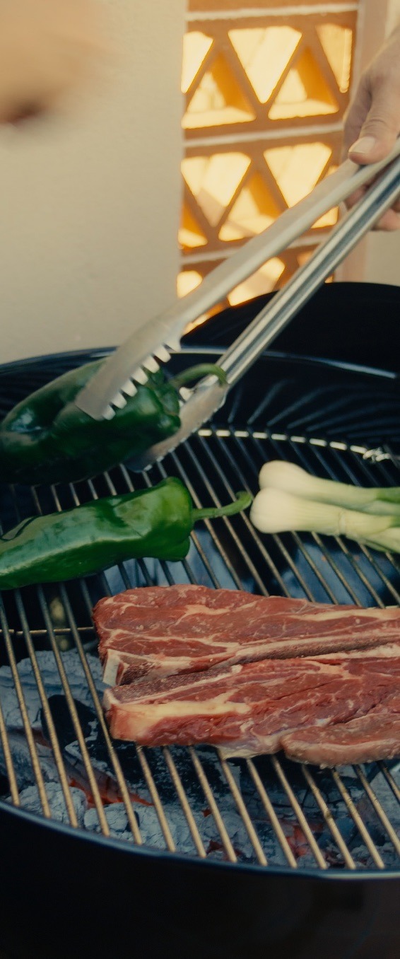 Cortes de carne, chiles y cebollitas sobre la parrilla