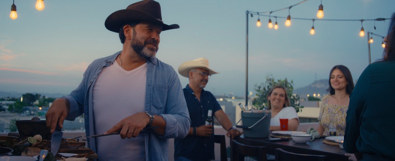 Amigos reunidos alrededor del asador en un rooftop al atardecer