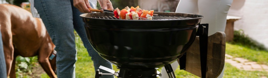 Asador tipo kettle con brochetas en un jardín