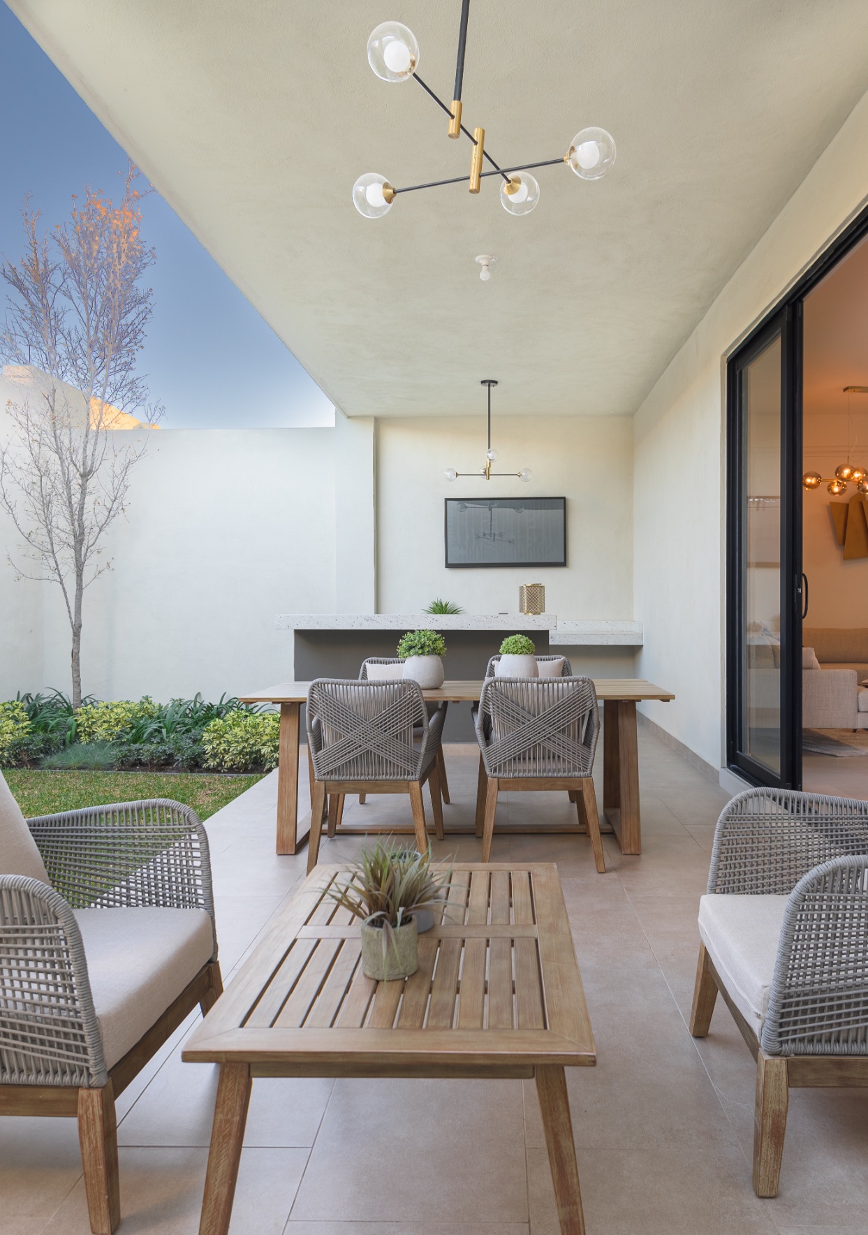Terraza techada con sala y comedor exterior junto al jardín