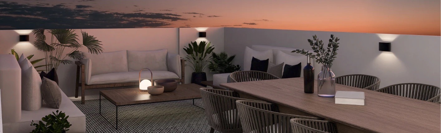 Terraza al atardecer con sala, comedor y apliques de luz en el muro
